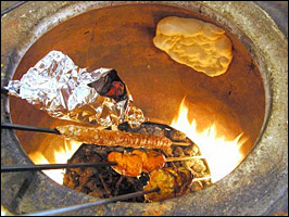 Kebabs and bread cook in a tandoor oven